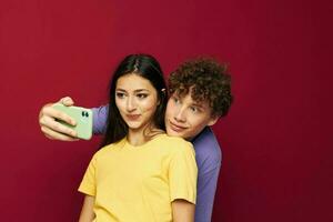 a young couple in colorful T-shirts with a phone isolated background photo