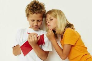 picture of positive boy and girl fun in colorful t-shirts with a notepad isolated background unaltered photo