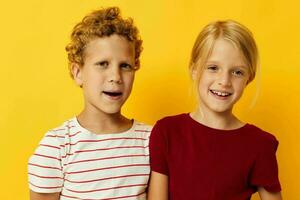 retrato de linda niños en pie lado por lado posando infancia emociones amarillo antecedentes foto