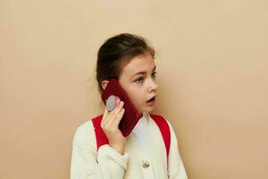 linda niña Chica de escuela mochila teléfono en mano aislado antecedentes foto