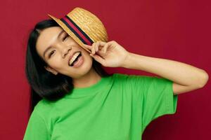 Portrait Asian beautiful young woman smile green t-shirt hat posing fashion red background unaltered photo