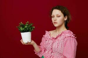 alegre mujer en rosado blusa flor en un maceta aislado antecedentes inalterado foto