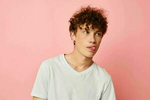 portrait of a young curly man in white t-shirt casual wear emotions pink background unaltered photo