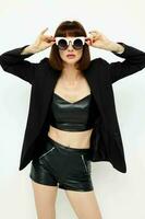 attractive woman posing with sunglasses a leather suit black jacket light background photo