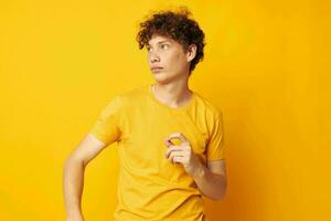 Young curly-haired man Youth style studio casual wear yellow background unaltered photo