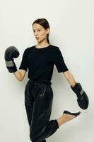 atlético mujer en boxeo guantes en negro pantalones y un camiseta aptitud formación foto