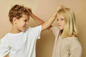 boy and girl holding each other by the hair beige background photo