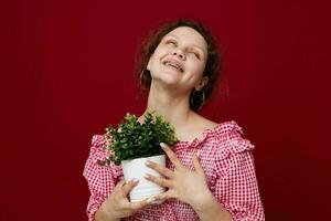 attractive young woman in pink blouse is posing with a plant in white pot photo