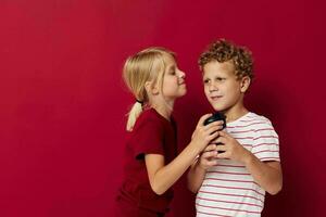 boy and girl are standing next to a disposable glass with a drink red background photo