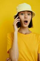 joven hermosa mujer en un amarillo sombrero juventud estilo casual hablando en el teléfono aislado antecedentes foto