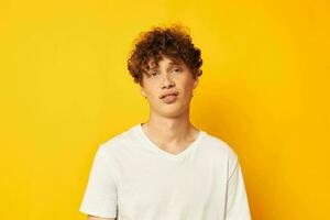 curly red-haired guy in a white t-shirt on a yellow background photo
