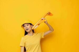 Charming young Asian woman cheerful woman with an airplane in the hands of fun yellow background unaltered photo