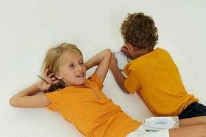 Small children drawing in notebooks lying on the floor light background unaltered photo