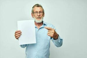 Portrait elderly man in a blue shirt and glasses a white sheet of paper unaltered photo