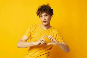 Young curly-haired man yellow t-shirt fashion hand gestures isolated background unaltered photo
