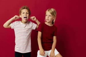 Cute preschool kids smiling and posing in casual clothes against red background photo