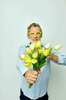 Senior grey-haired man a bouquet of flowers with glasses as a gift light background photo