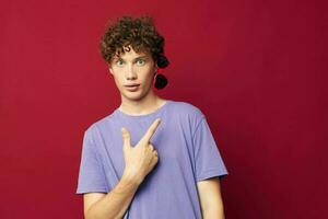 guy with red curly hair guy in a purple t-shirt with sunglasses posing red background photo