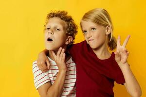 two joyful children standing side by side posing childhood emotions on colored background photo