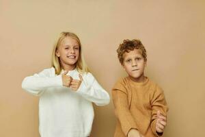 pequeño chico y niña en pie siguiente a posando emociones aislado antecedentes foto