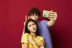 Man and woman in colorful T-shirts with a phone isolated background photo