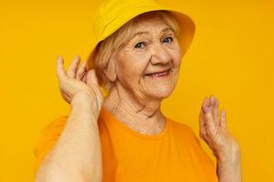 smiling elderly woman in yellow t-shirts hat posing isolated background photo