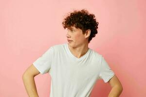 portrait of a young curly man in white t-shirt casual wear emotions pink background unaltered photo