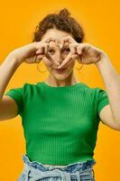 cute girl in a green t-shirt gestures with hands emotions yellow background photo