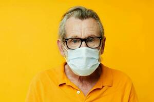 Portrait elderly man medical mask on the face protection close-up yellow background photo