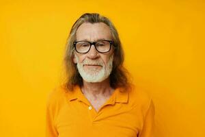 Gray-haired elderly man with a beard wearing glasses close up yellow background photo