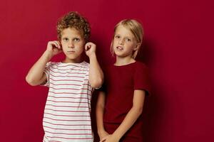 two joyful children emotions stand side by side in everyday clothes on colored background photo