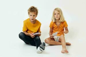 Small children drawing in notebooks lying on the floor light background unaltered photo