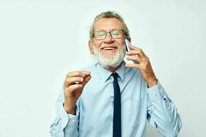 Photo of retired old man in a shirt with a tie talking on the phone isolated background