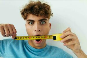 handsome guy yardstick in hand in blue t-shirts isolated background photo