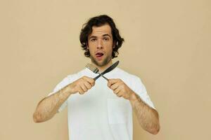 hermoso hombre en un blanco camiseta con cuchillo con tenedor aislado antecedentes foto