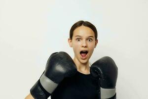 young woman in black sports uniform boxing gloves posing isolated background photo