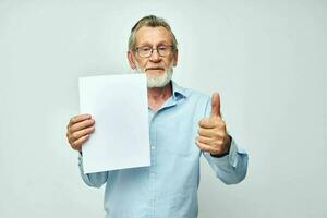 Portrait elderly man in a blue shirt and glasses a white sheet of paper unaltered photo