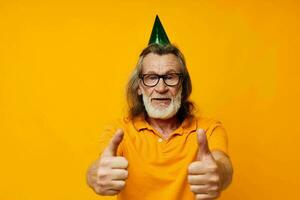 retrato mayor hombre en un amarillo camiseta con un gorra en su cabeza divertido amarillo antecedentes foto