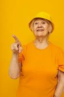 Photo of retired old lady in yellow t-shirts hat posing isolated background