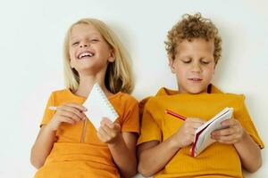 Small children lie on the floor with notepads and pencils isolated background unaltered photo