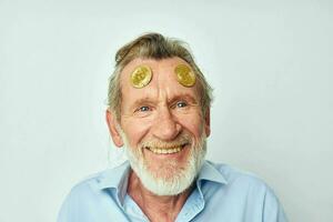 Portrait elderly man in a blue shirt bitcoins on the face light background photo