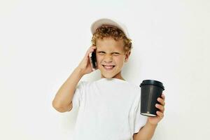 linda pequeño chico hablando en el teléfono con un negro vaso ligero antecedentes inalterado foto