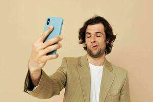 hombre en un traje posando emociones mirando a el teléfono beige antecedentes foto