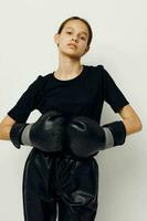 joven hermosa mujer en boxeo guantes en negro pantalones y un camiseta ligero antecedentes foto