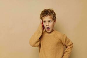 curly boy talking on the phone posing beige background photo