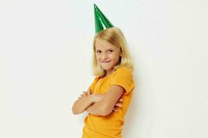 un niña con un verde gorra en su cabeza gestos con su manos foto