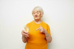 Cheerful elderly woman in casual t-shirt glasses glass of water cropped view photo