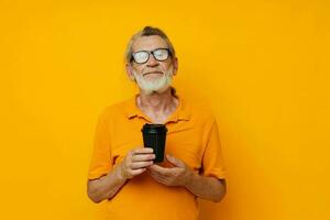 Portrait of happy senior man in a yellow T-shirt a glass with a drink cropped view photo