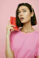 beautiful girl in a pink t-shirt red notebook and pen Lifestyle unaltered photo