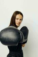 joven hermosa mujer en boxeo guantes puñetazo en negro pantalones y un camiseta estilo de vida inalterado foto